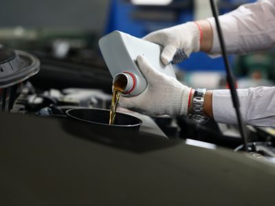 Mecãnico aplicando lubrificante mineral no motor de um carro