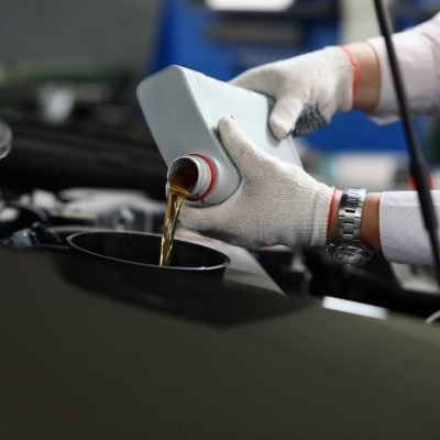 Mecãnico aplicando lubrificante mineral no motor de um carro